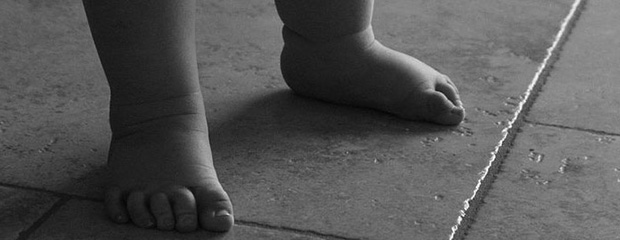 A black and white image of a baby's feet on a tiled floor