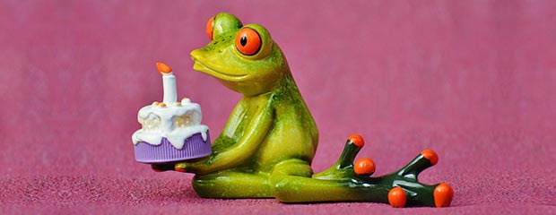 A frog figurine, holding a birthday cake